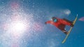 BOTTOM UP: Snowboarder flies through the air and does a trick in sunny sky.
