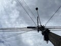 Point of view of a pole full of wires on a gray cloudy sky day, parallel and perpendicular lines