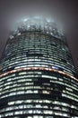 A bottom-up view of the facade of a modern office building at night in fog. Light of the night city. Moscow City Royalty Free Stock Photo