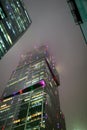 A bottom-up view of the facade of a modern office building at night in fog. Light of the night city. Moscow City Royalty Free Stock Photo