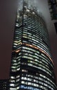 A bottom-up view of the facade of a modern office building at night in fog. Light of the night city. Moscow City Royalty Free Stock Photo