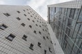 Bottom up view of the facade of an old Soviet modernist building lined with ceramic tiles with wide and small windows.