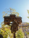 Bottom up view of a small decorative wooden house standing on a wooden pole against a blue sky and tree branches Royalty Free Stock Photo