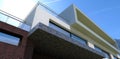 A bottom view of advanced architecture. Rectangular shapes, bright finishing materials. Lots of glass and metal. The sun in the