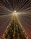 Bottom view of a beautiful big Christmas tree with balls and luminous garlands on a background of dark night sky Royalty Free Stock Photo