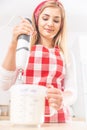 Bottom view of a beautiful girl in a red checkered apron whisking egg whites in the kitchen Royalty Free Stock Photo