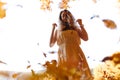 Bottom view of beautiful playful woman surrounded by yellow leaves on background of autumn forest and sky Royalty Free Stock Photo