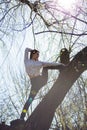 Bottom view charming cute slim girl gymnast is on top of unusual tree without leaves and executes elements of stretching