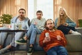 Bottom view of cheerful group of friends sitting on sofa in living room and watching football match. Soccer championship Royalty Free Stock Photo