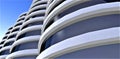 Bottom view of the contemporary office building with round facade against the blue sky. Mirrored glass exterior. 3d rendering