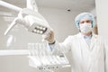 Bottom view of a doctor portrait dentist, surgeon in uniform and mask on his face, wearing glasses, holding lamp in her