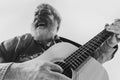 Bottom view of emotional senior bearded man, musician playing guitar isolated on white background. Rehearsal base