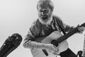 Bottom view of emotional senior bearded man, musician playing guitar isolated on white background. Rehearsal base