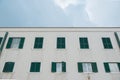 bottom view of european building with shuttered windows in front of cloudy sky,