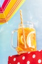 Bottom View Of Glass Mug With Frosty Orange Lemonade, Cocktail Over Blue Sunny Sky Background. Vacation, Happiness