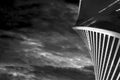 Bottom view of glass skyscraper in shape of spiral on the background of dramatic dark sky with clouds. Black and white shot of Royalty Free Stock Photo