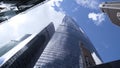 Bottom view of glass skyscrapers on background blue sky. Action. Dizzying view of business high-rise in center of modern