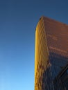 Bottom view of golden skyscraper against blue sky.