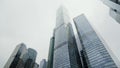 Bottom view of high rise buildings with glass windows and the cloudy foggy sky. Action. Beautiful modern skyscrapers in Royalty Free Stock Photo