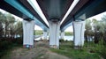 Bottom view of a huge flyover motorway, blue sky, large pillars with sunlight.