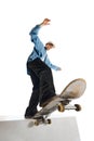 Bottom view image of teen boy in casual clothes in motion, training, doing stunts on skateboard isolated over white Royalty Free Stock Photo