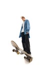 Bottom view image of teen boy in casual clothes standing with skateboard isolated over white background Royalty Free Stock Photo