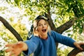 The bottom view image of a young blonde woman has fun on the tree, on nature background in the park. Happy female sitting gon the Royalty Free Stock Photo