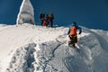 bottom view of man in ski suit holding a rope and climbing snowy mountain slope Royalty Free Stock Photo