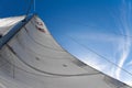 Bottom view of mast and sail of yacht on blue sky background, selective focus