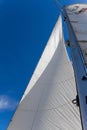 Bottom view of mast and sail of yacht on blue sky background, selective focus