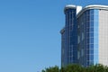 Bottom view of a modern office building and trees against a blue sky background. Summer city landscape. Royalty Free Stock Photo