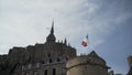 Bottom view of Mont Saint Michel castle in France on blue cloudy sky background with flying seaguls. Action. Beautiful Royalty Free Stock Photo