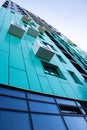 bottom view of a multi-storey modern aqua colored building . urban jungle