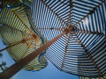 Bottom view of the multicolored colored striped beach umbrellas against the sky and