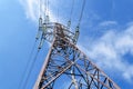 Bottom view of an power pylon and high-voltage wires with glass fuses against a bright blue sky with white clouds on a sunny day. Royalty Free Stock Photo