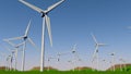 Bottom view of a set of turbines forming a Wind Farm on a green field during the day with the cloudy blue sky. Royalty Free Stock Photo