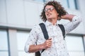 Bottom view shot of handsome young male student with backpack standing at building background on the street, thinking where to go Royalty Free Stock Photo