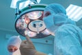 Bottom view of surgeons in the operating room, in sterile masks, preparing for surgical intervention, arms raised up, in sterile