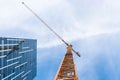 Yellow tower crane. Bottom view of a tall construction crane next to a modern building.