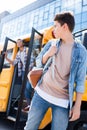 bottom view of teen schoolboy walking in front of school bus and turning back