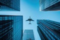 Bottom view to airplane flying above glass office buildings Royalty Free Stock Photo