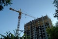 Bottom view of a tower crane and a high-rise apartment building under construction in the morning sun against a blue sky. Royalty Free Stock Photo