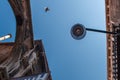 Bottom view of Traditional street lamp at an old Venetian house in the middle of the day with a flying bird in a blue