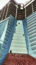 Bottom view of an unfinished skyscraper with glass walls and windows of a futuristic shape. An example of modern urban