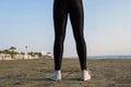 Bottom view of woman legs in the sport leggings and sneakers on the beach at the morning Royalty Free Stock Photo