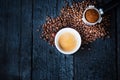 Bottomless filter with grind beans on a wooden black table and cup of espresso coffee. Roasted coffee beans. Espresso coffee extra