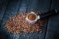 Bottomless filter with grind beans on a wooden black table. Roasted coffee beans. Espresso coffee extraction. Prepare of espresso. Royalty Free Stock Photo