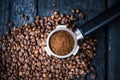 Bottomless filter with grind beans on a wooden black table. Roasted coffee beans. Espresso coffee extraction. Prepare of espresso. Royalty Free Stock Photo