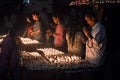 Boudhanath, Kathmandu, Nepal. 09/2014. candles being lit at night as people pray at the Buddhist temple of Boudhanath.