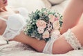 Boudoir wedding morning. Beautiful sexy bride in white underwear with garter belt and bouquet in soft defocus